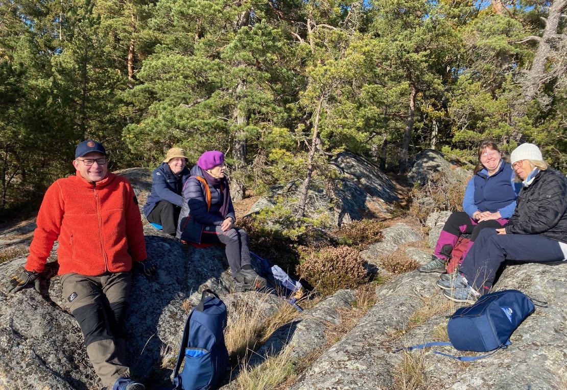 Glada friluftsmänniskor njuter av höstsolen på berget